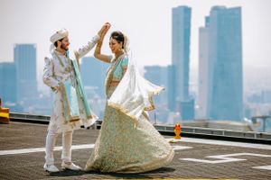 Wedding couple poses against modern city skyline with tall buildings in the background.
