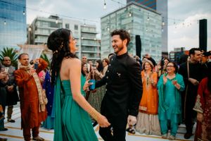 Outdoor wedding celebration with guests in teal and brown formal attire against urban backdrop.