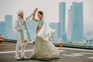 Couple shares romantic dance moves with urban skyline backdrop during wedding celebration.