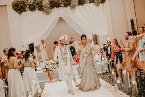 Wedding guests celebrate during a joyous reception in an elegant white-draped venue.