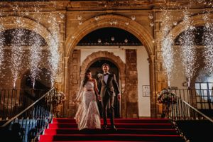 Grand entrance with sparklers illuminating stone archways during wedding ceremony.