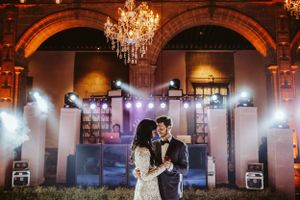 Elegant ballroom with crystal chandeliers and arched architecture set for wedding celebration.