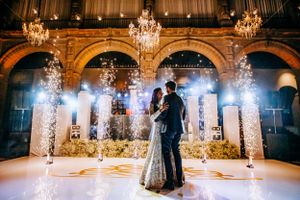 First dance in ornate ballroom with dramatic lighting and sparkling effects.