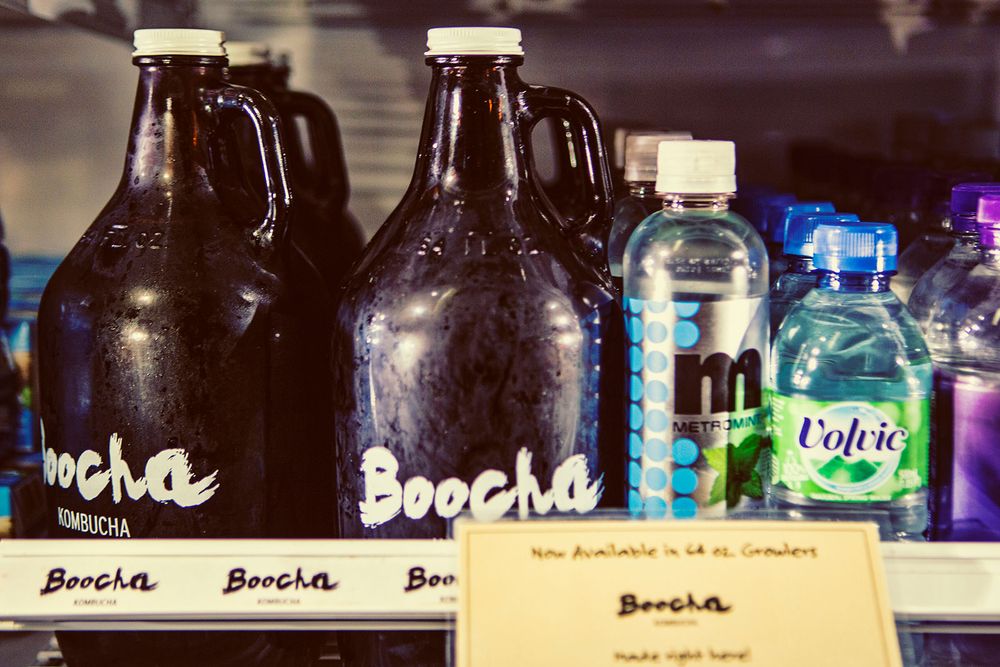Boocha kombucha brand dark glass growler bottles displayed on a retail store shelf.