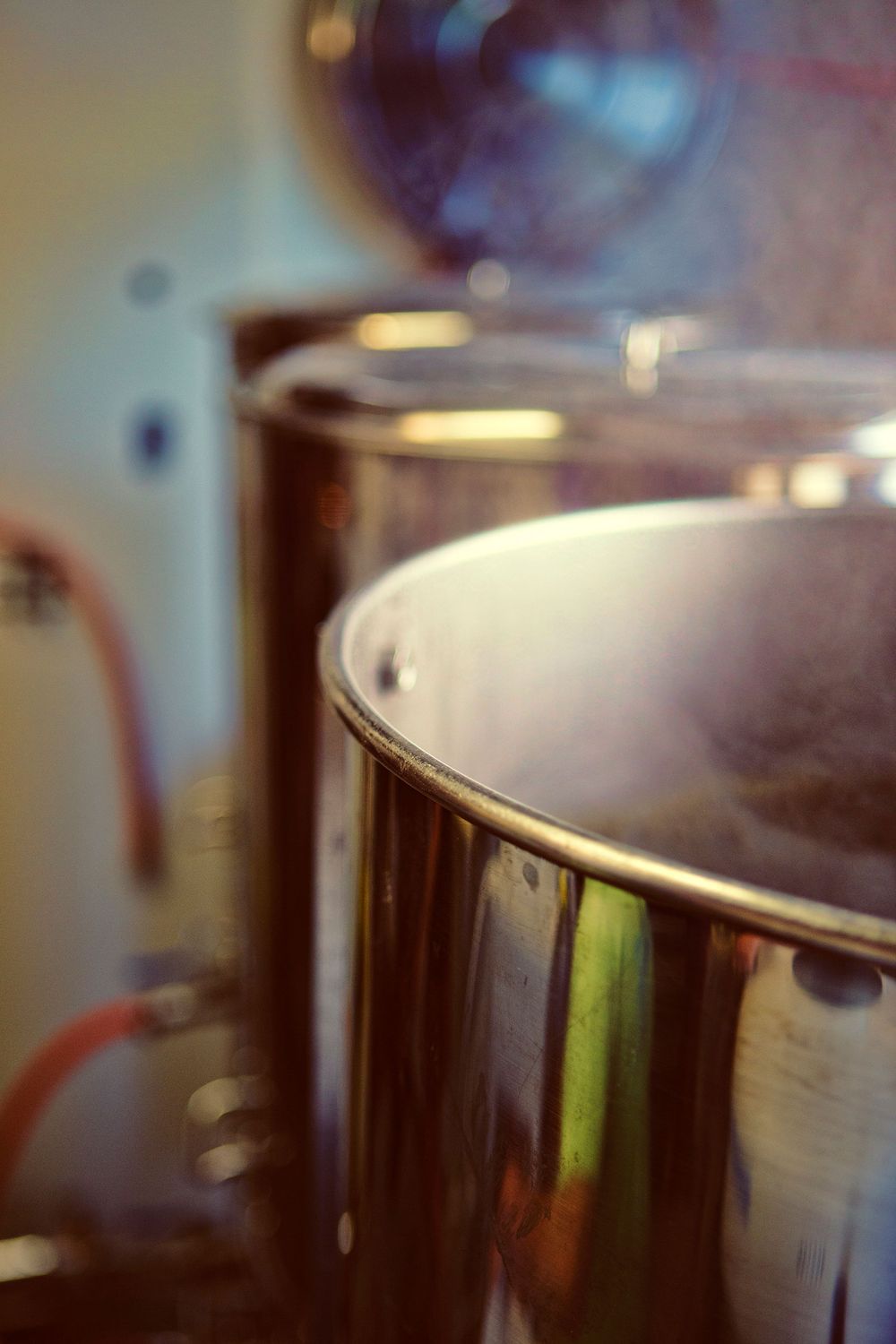 Close-up of stainless steel brewing kettle with steam in a craft brewery.