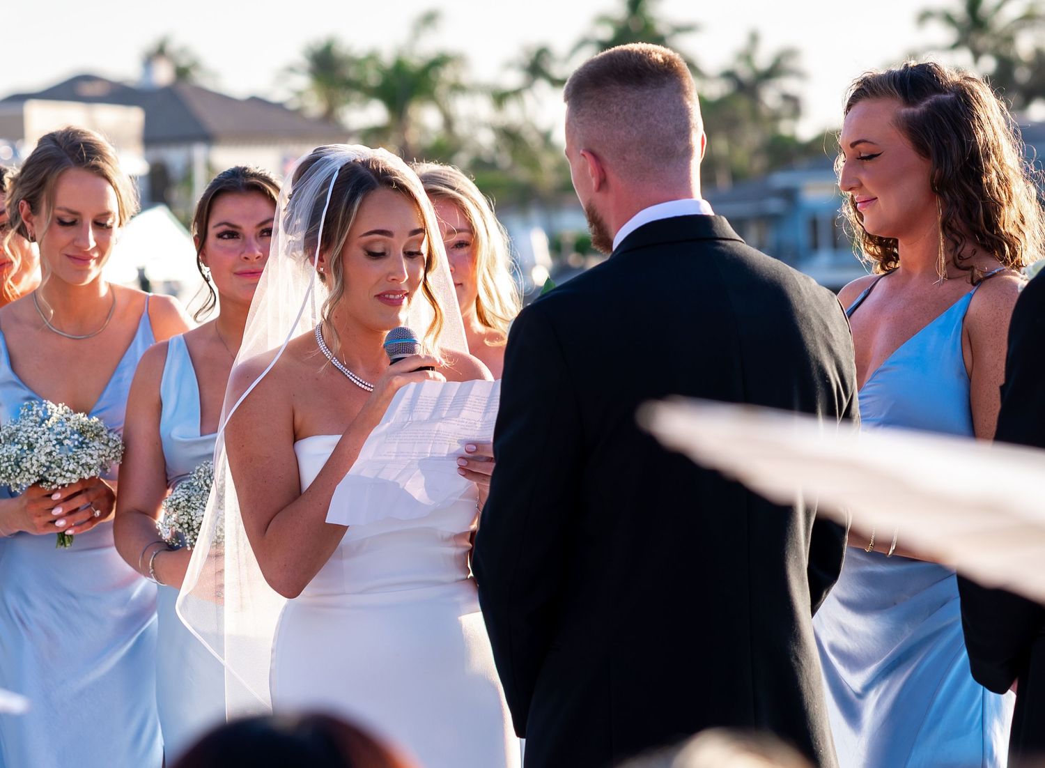 Backlit by the setting sun during their vow exchange at their Treasure Coast estate wedding ceremony.