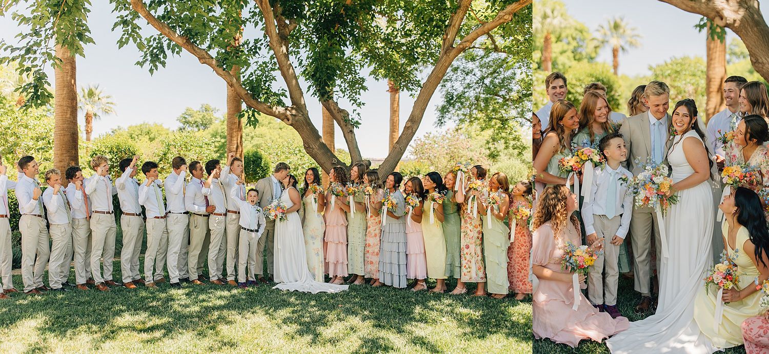 Large wedding party poses outdoors under trees, with bridesmaids in pastel dresses and groomsmen in tan suits.