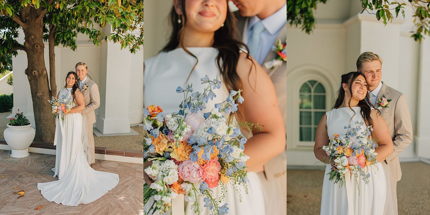 Wedding couple posing with colorful bridal bouquet of blue, orange, and pink flowers outside elegant white venue.