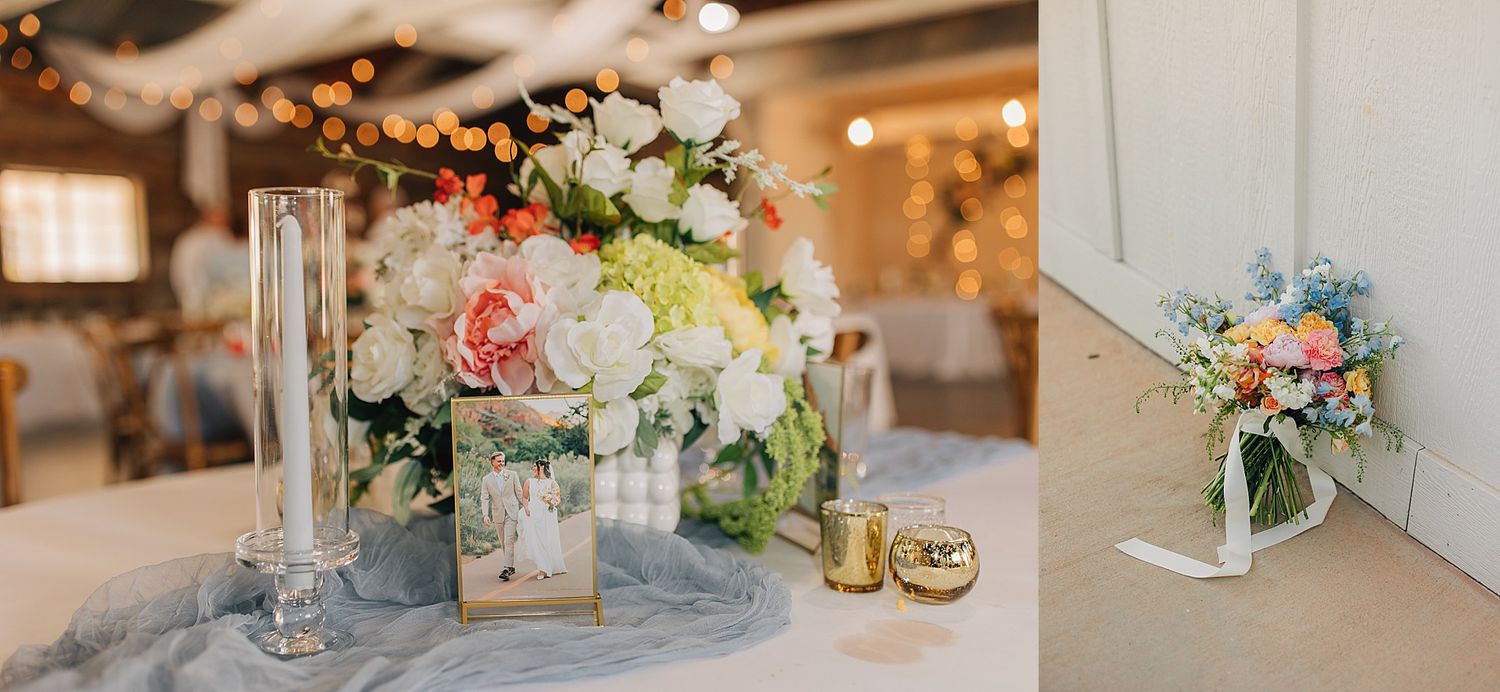 Elegant wedding reception table with white and coral floral centerpiece, candles, and gold accents on a blue linen.