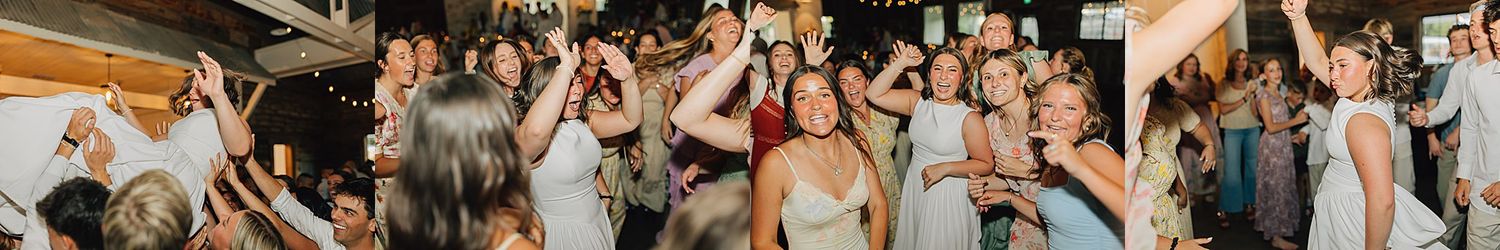 Joyful wedding reception guests dancing and celebrating together in a warmly lit venue.