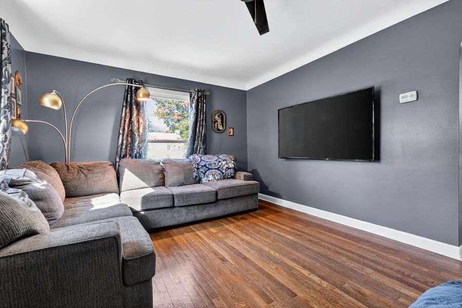 Spacious living room with gray walls, hardwood floors, large sectional sofa, and wall-mounted flat screen TV.