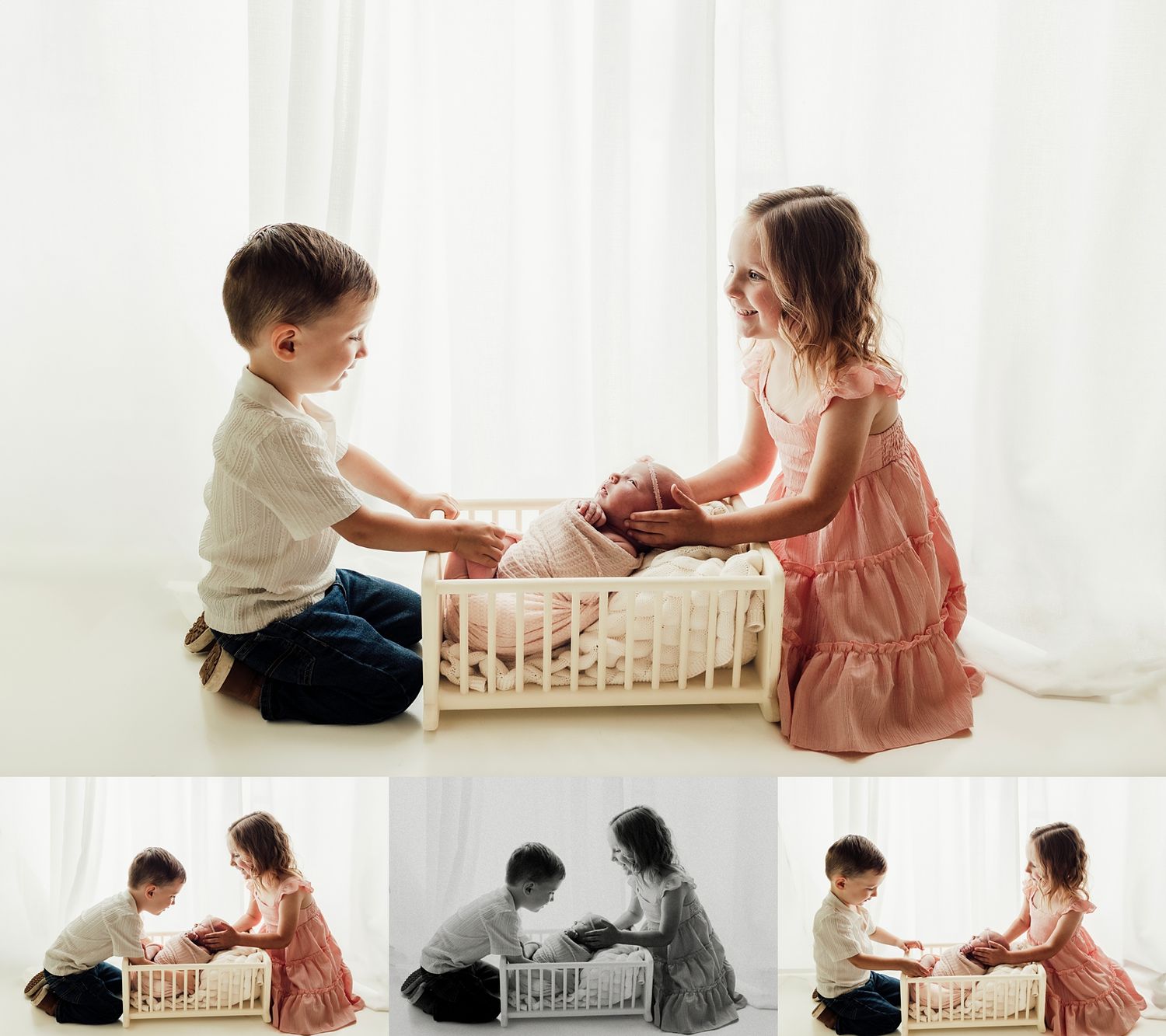 Two young siblings kneel beside a small wooden doll bed, tenderly interacting in a bright, airy studio setting.