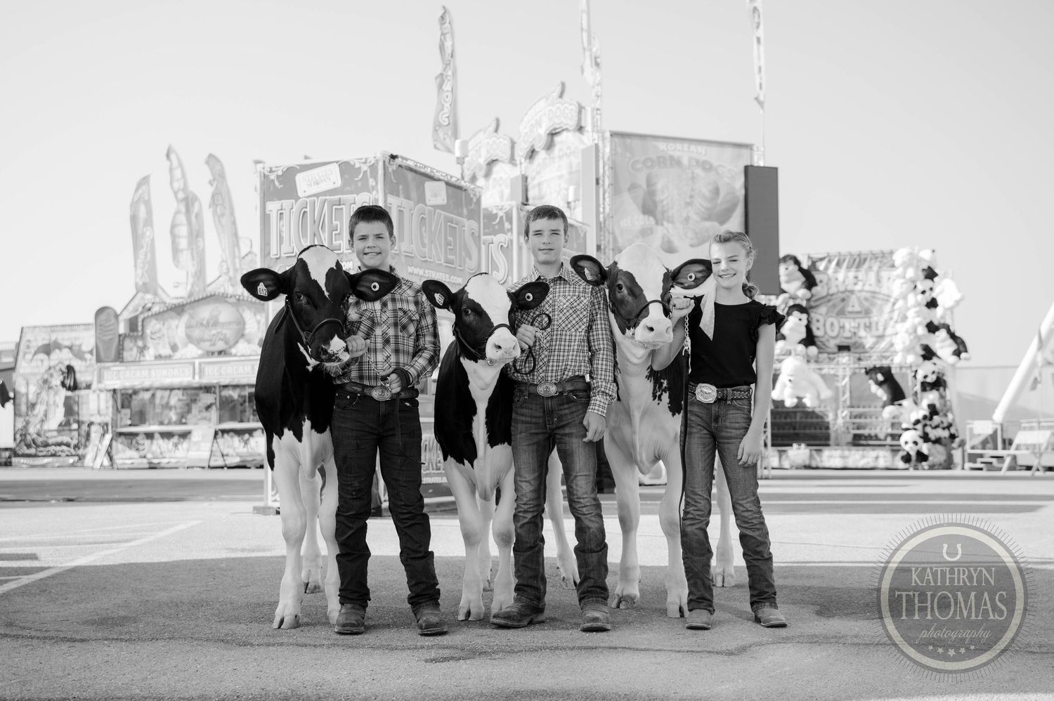 A young exhibitor proudly holds a black and white dairy cow at a county fair with a Ferris wheel in the background.
