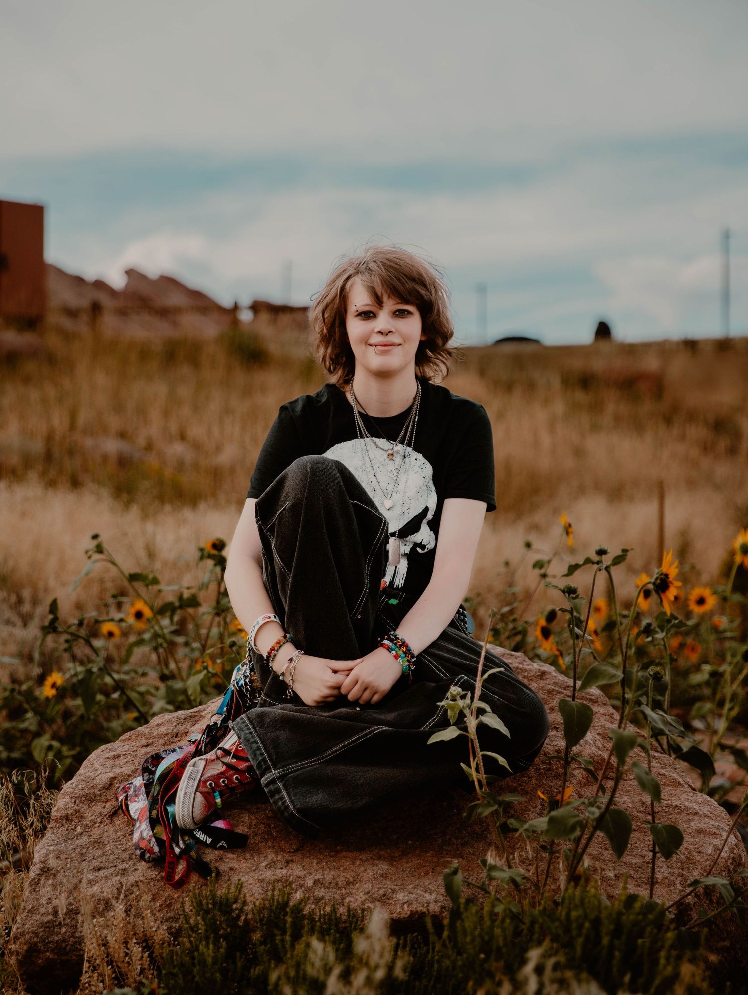Boy sits down, smiles, and poses for senior photos, cinematic, mountain, and portrait photos in Morrison, Colorado outside and in nature