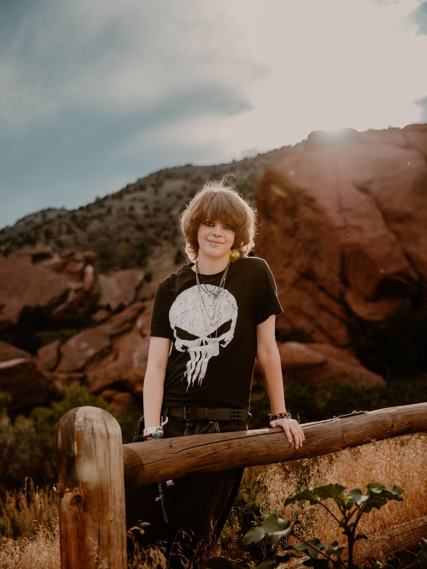Boy leans on fence and poses for senior photos, cinematic, mountain, and portrait photos in Morrison, Colorado outside and in nature