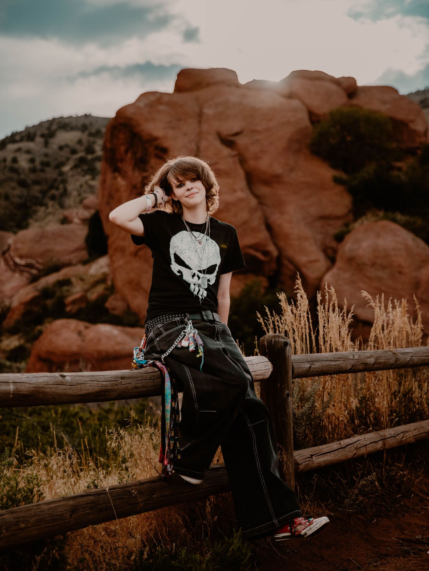 Boy sits on fence, and poses for senior photos, cinematic, mountain, and portrait photos in Morrison, Colorado outside and in nature