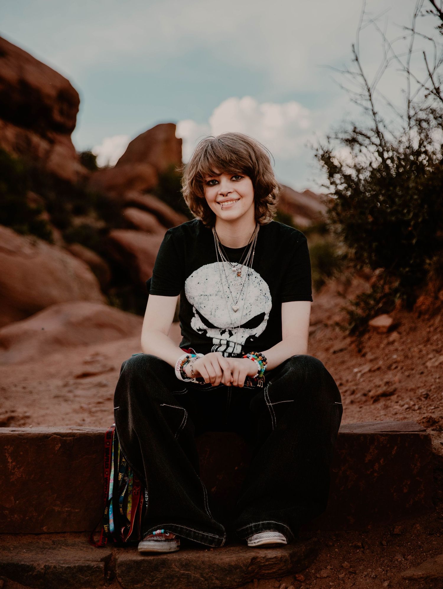 Boy sits down, smiles, and poses for senior photos, cinematic, mountain, and portrait photos in Morrison, Colorado outside and in nature