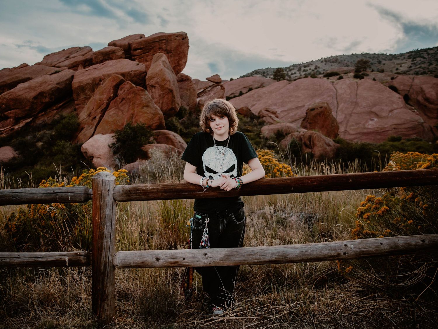 Boy leans on fence, and poses for senior photos, cinematic, mountain, and portrait photos in Morrison, Colorado outside and in nature