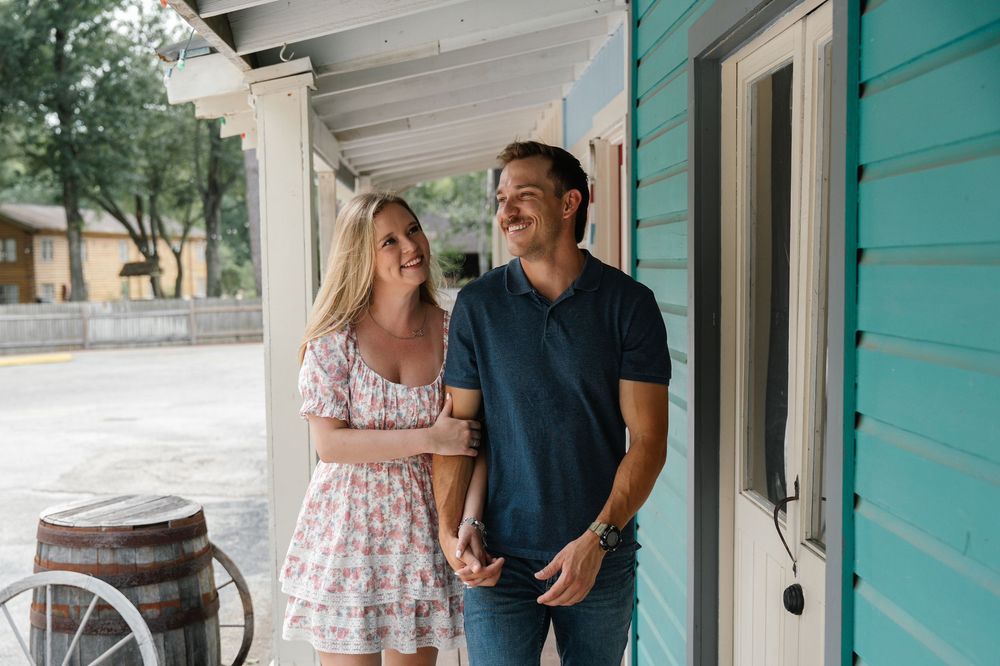 Couple laughing together on the porch of a charming turquoise building.