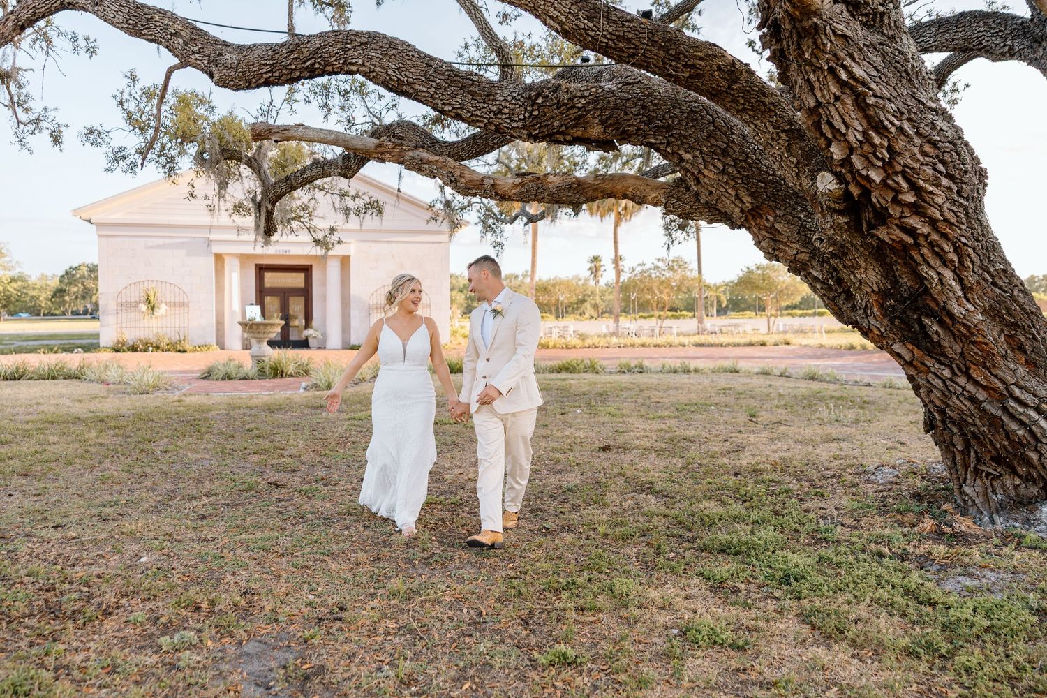 Bride and groom walking hand in hand outdoors during their wedding day.