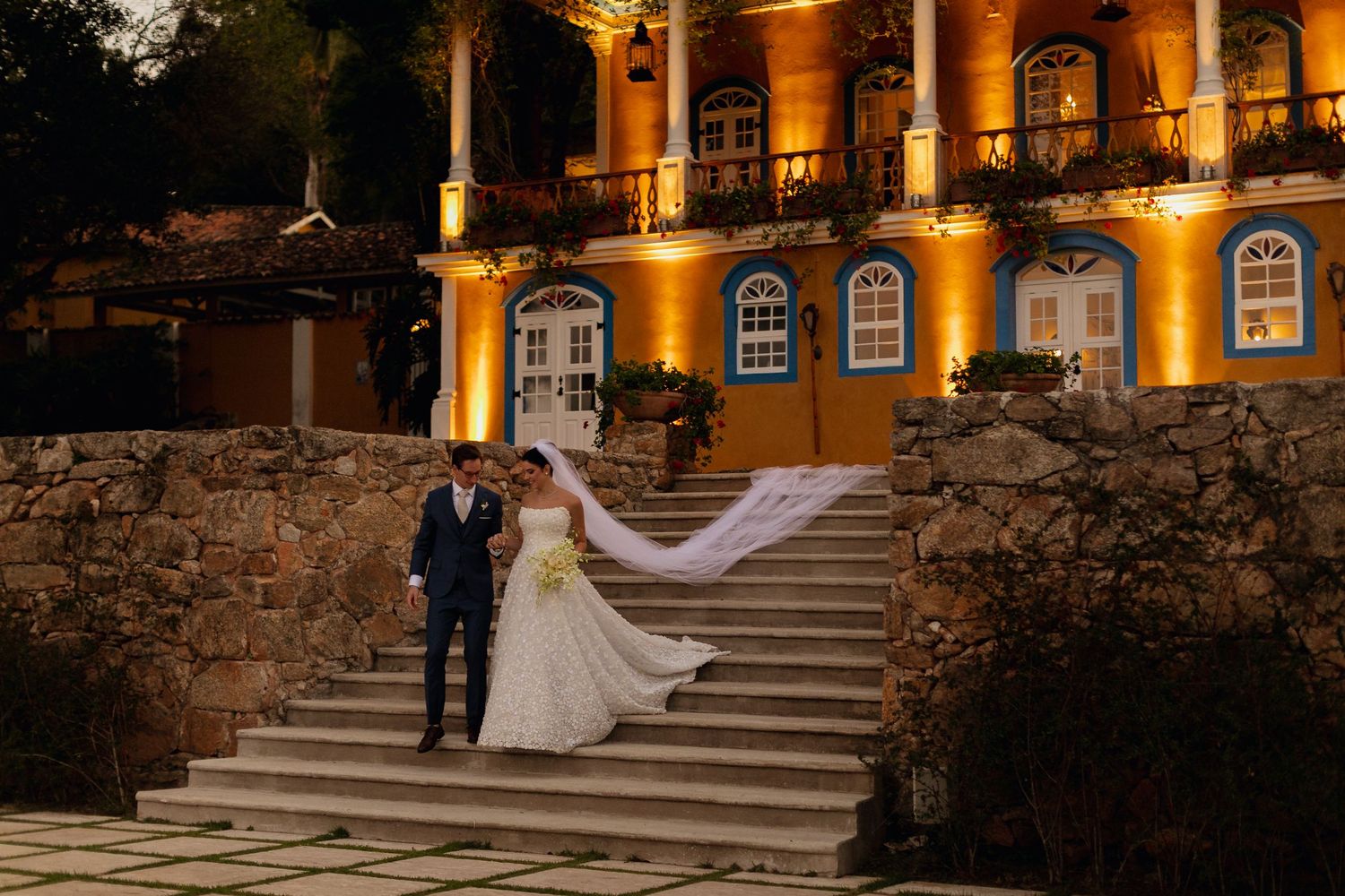 Black and white wedding photos of a couple walking through an elegant arched colonnade.