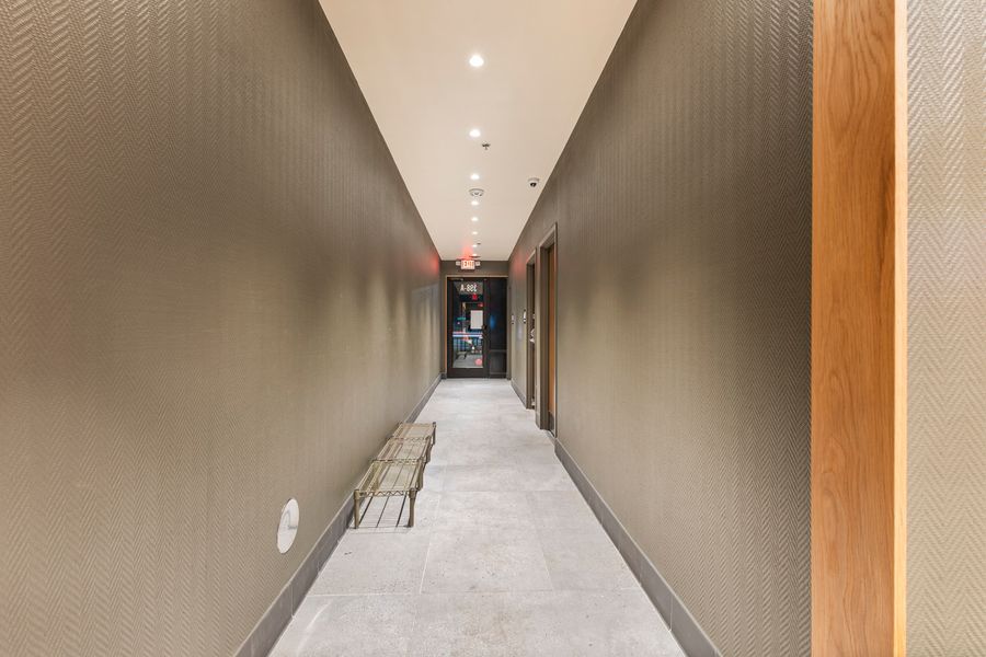 Modern commercial building corridor with textured gray walls, recessed lighting, and polished concrete floors.