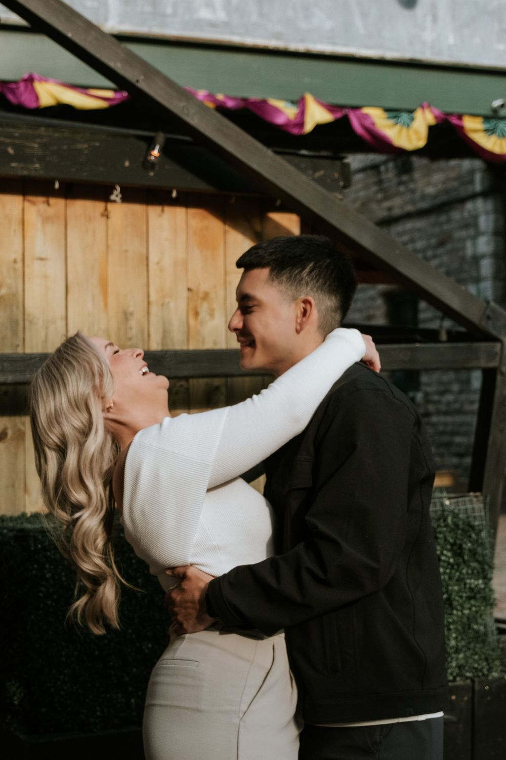 A joyful moment shared under string lights against wooden paneling.