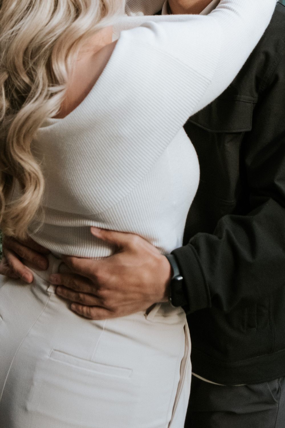 Close-up shot of an embrace showing white sweater and black jacket details.