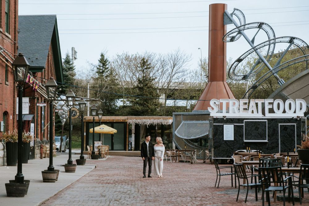 An urban street scene with a Streetfood sign and outdoor dining area in a historic brick district.