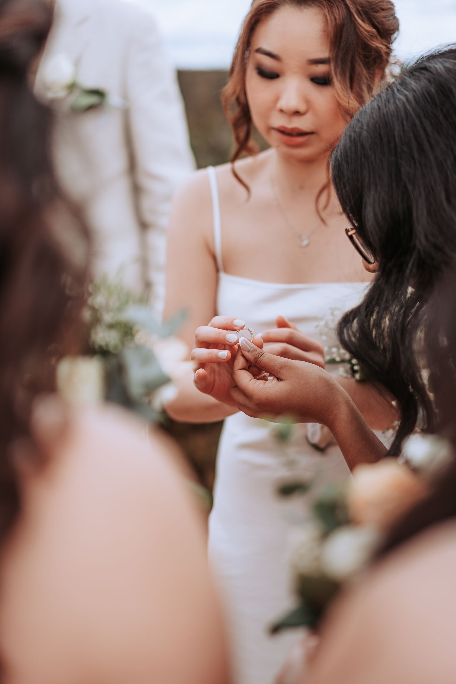 A close-up shot of hands exchanging rings during an intimate ceremony moment.