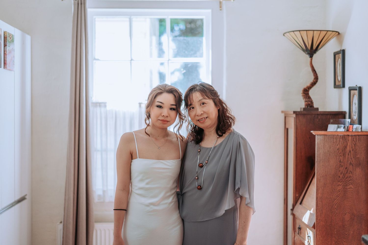 Two people in light colored clothing standing together in bright interior room.
