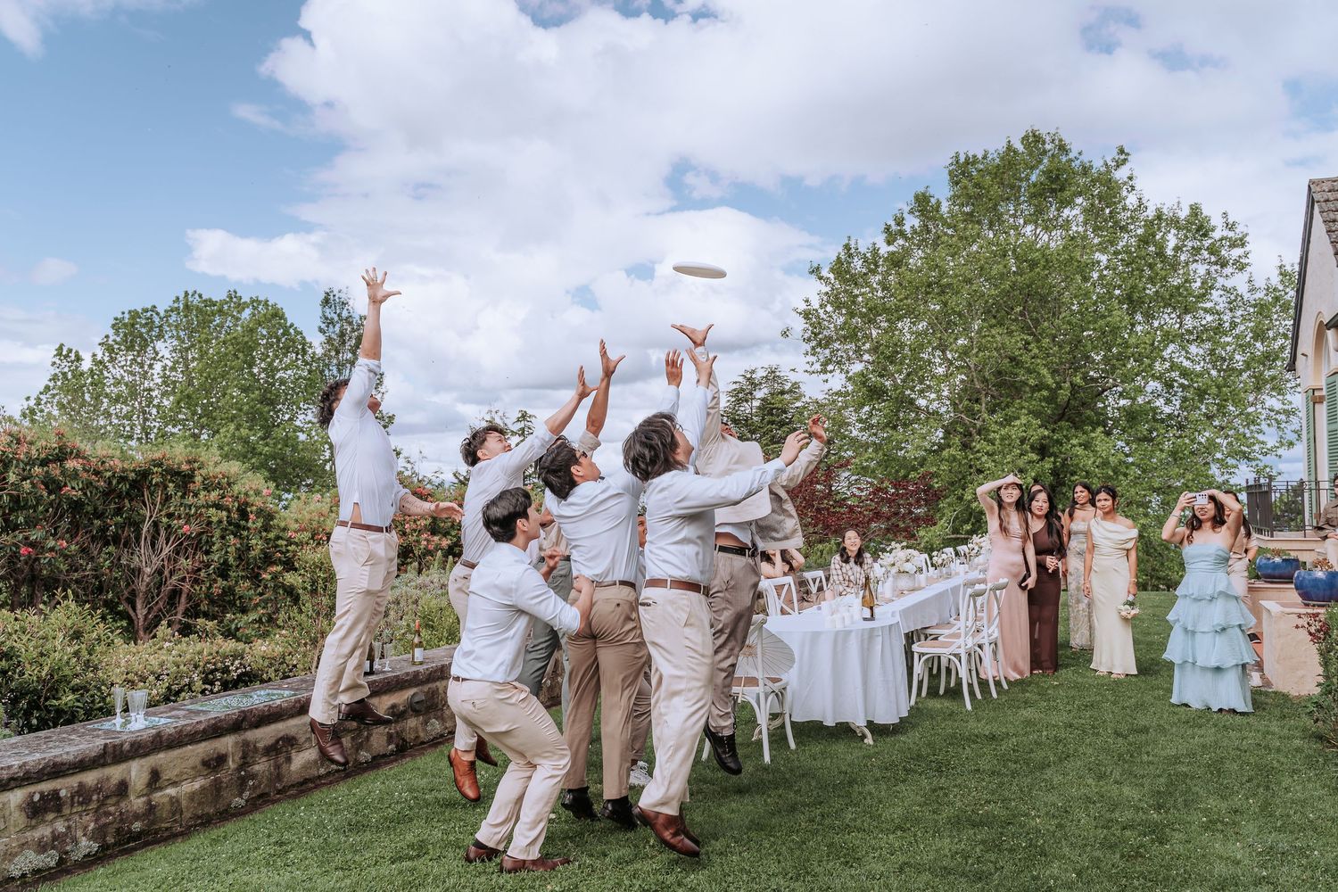 Joyful celebration moment with guests jumping and cheering on manicured lawn.
