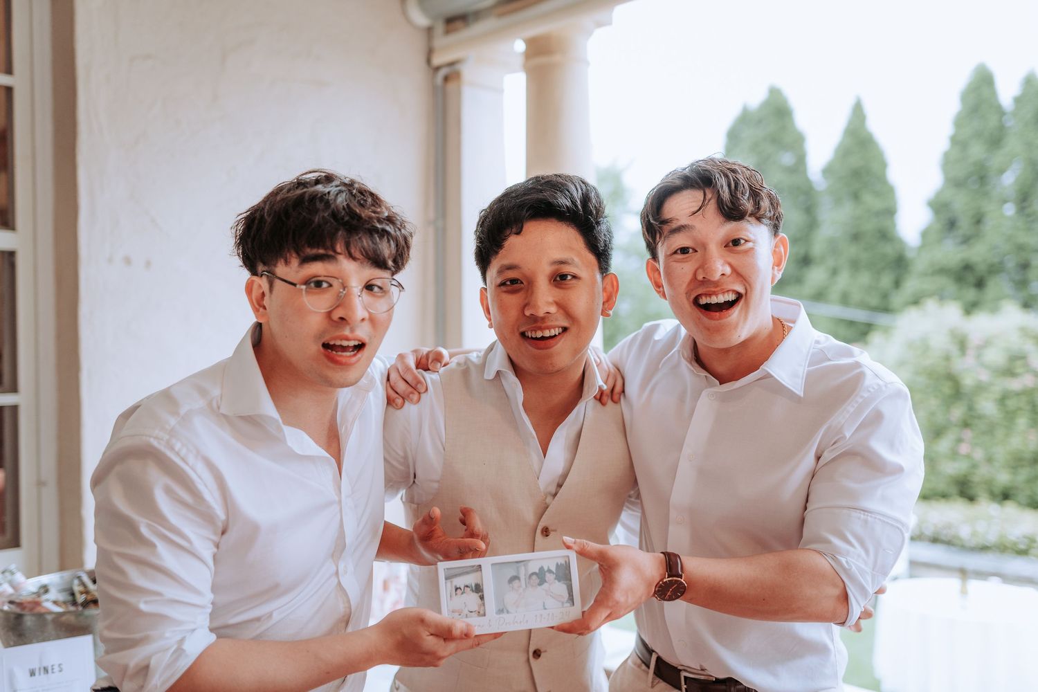Three people in white shirts share a laugh while looking at something together.