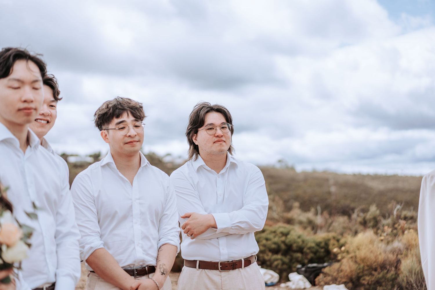 A group stands together in white shirts against a cloudy mountain backdrop.