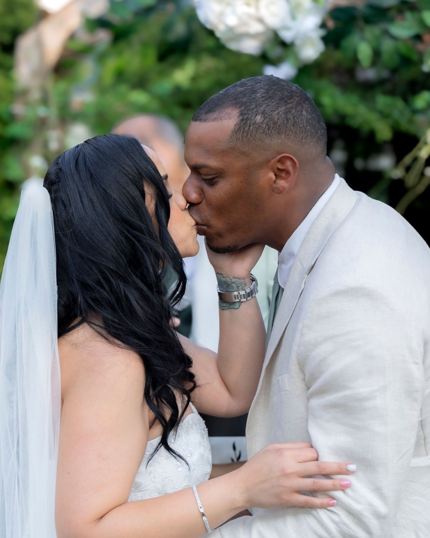 A romantic wedding kiss moment captured in an outdoor garden setting.