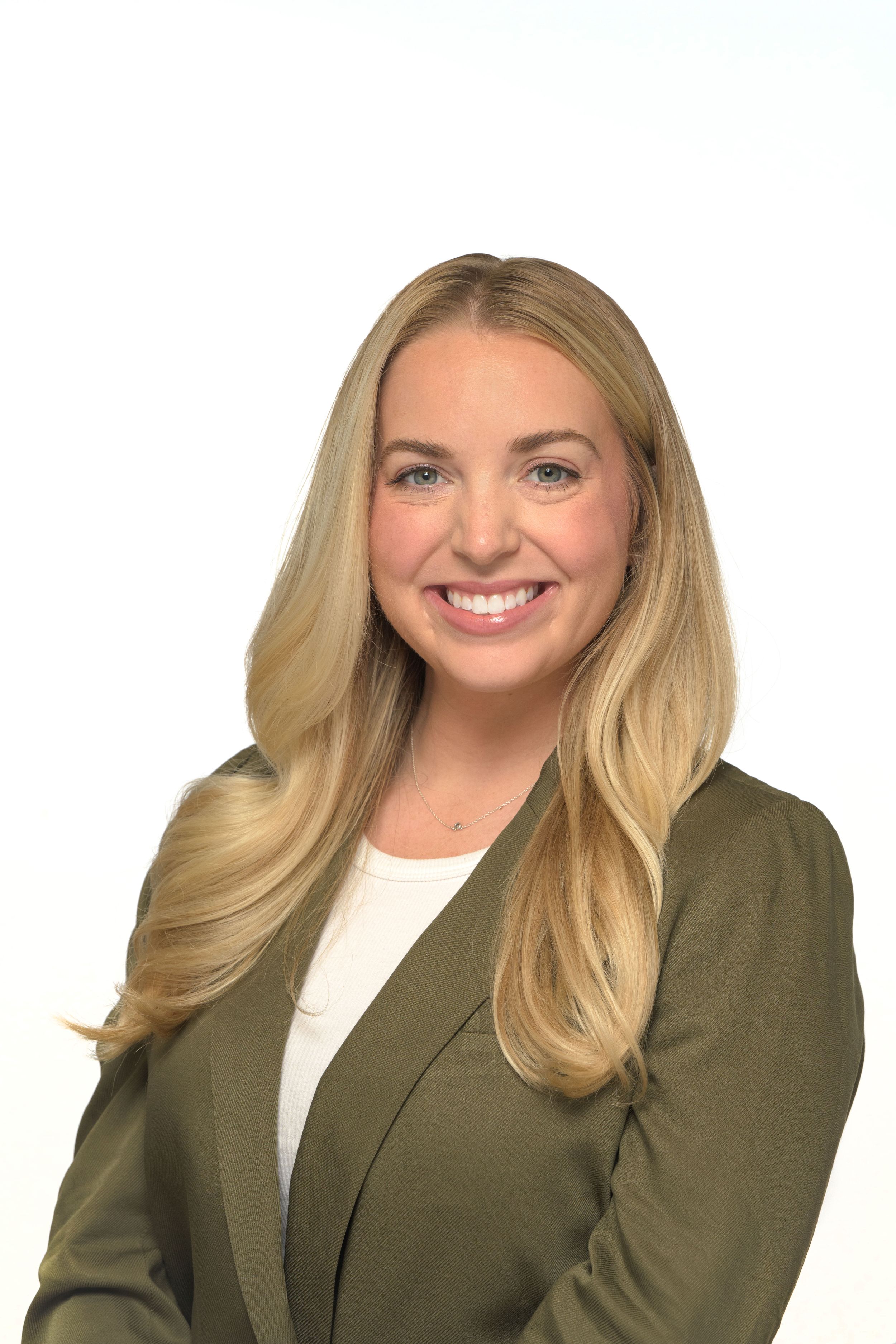Smiling blonde woman in an olive green blazer poses for a professional headshot.