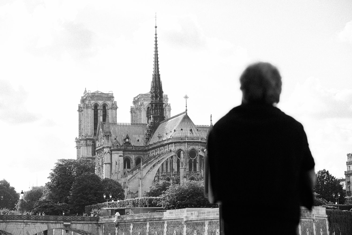 Silhouetted figure gazing at Notre Dame Cathedral in Paris in black and white.