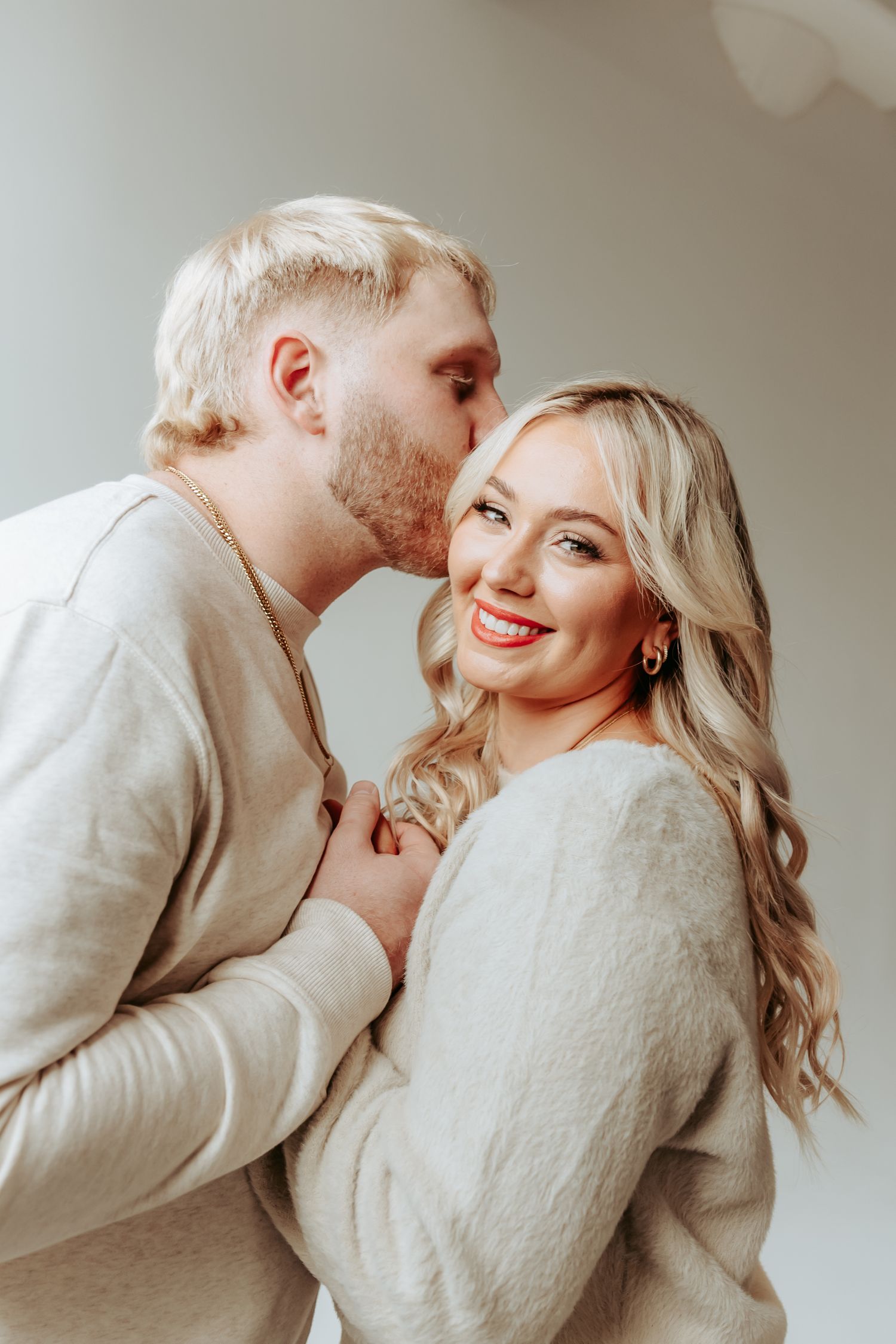 Loving couple in matching cream sweaters sharing a sweet moment together.