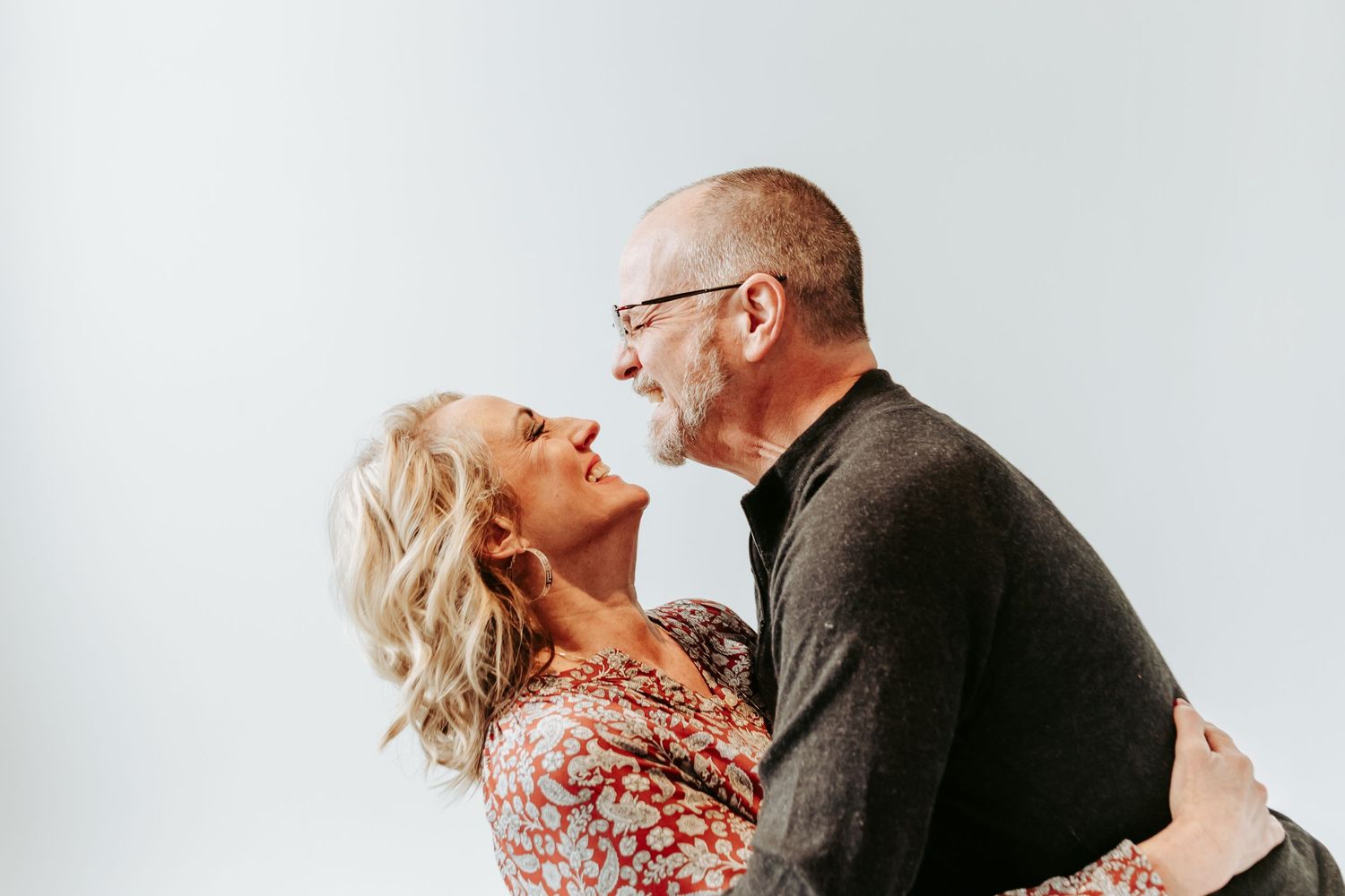 Mature couple sharing an affectionate moment against white background.