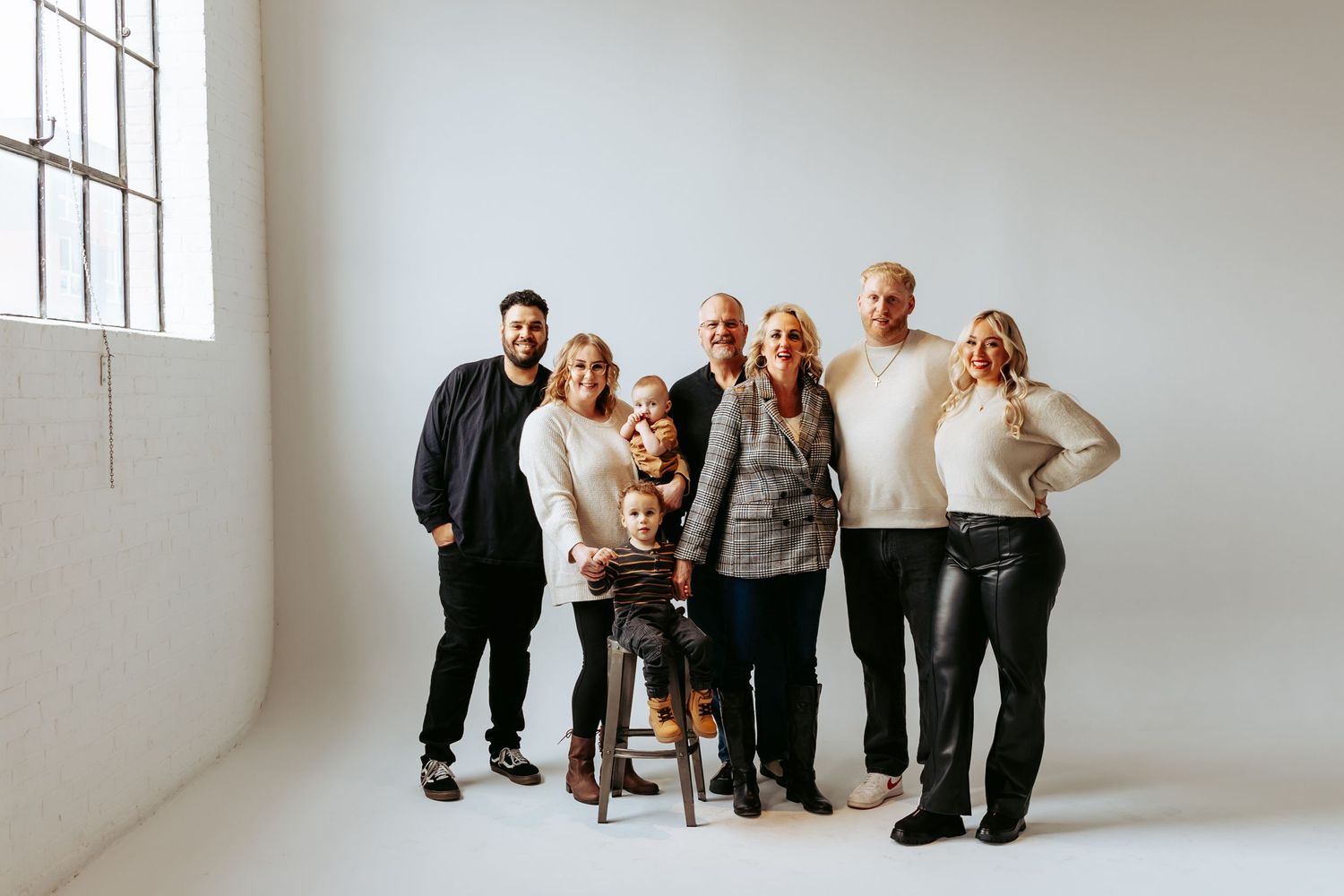 Multi-generational family group portrait against white studio background.