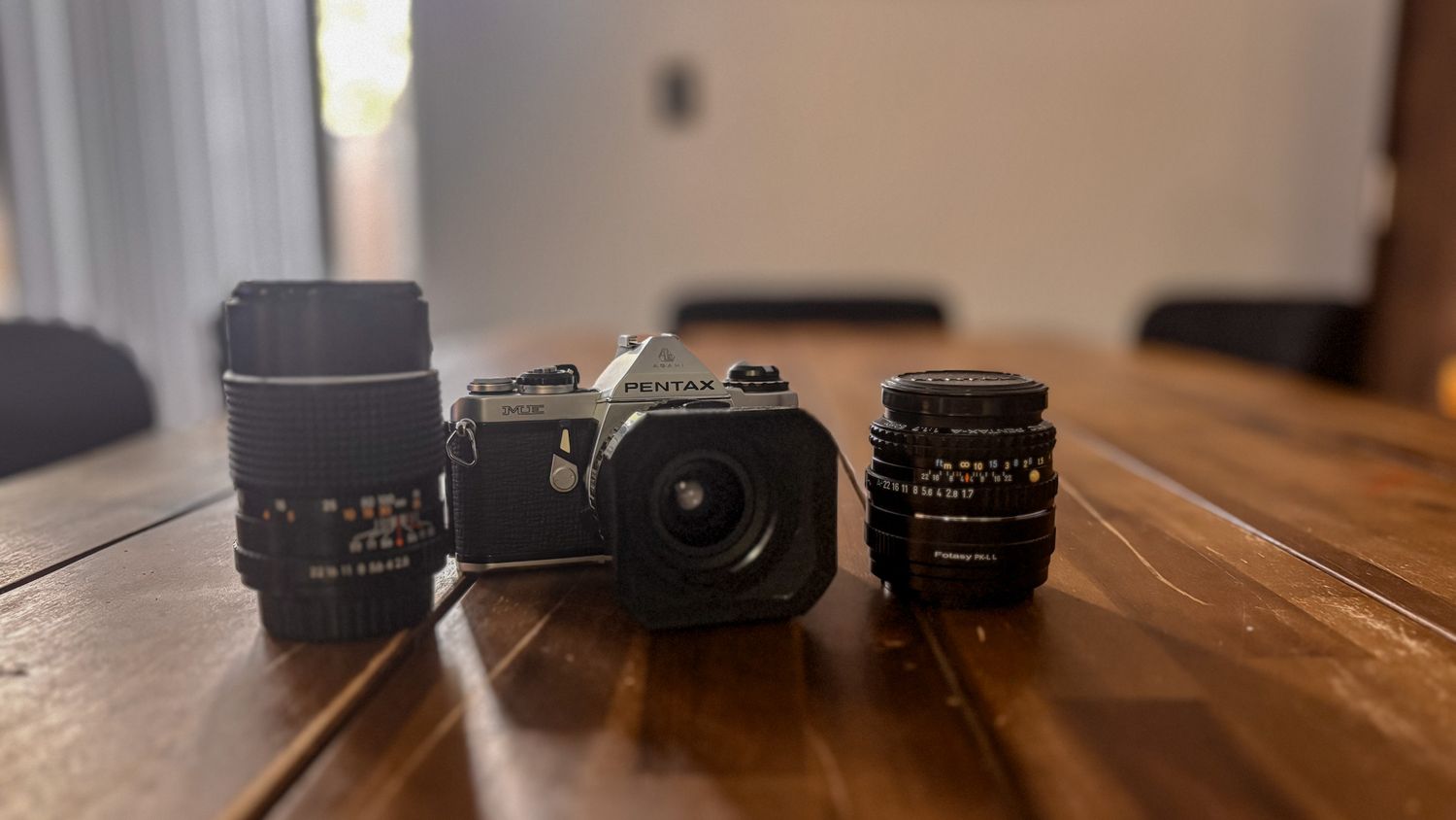 Vintage camera lenses and bodies arranged on a wooden table surface.