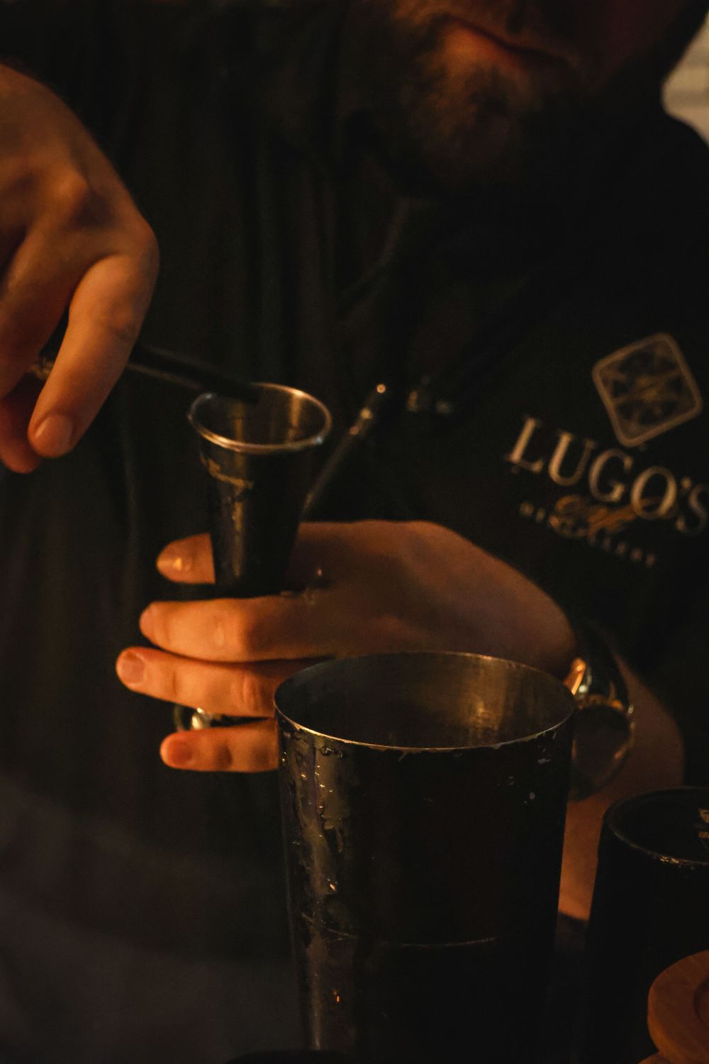 Bartended pouring a drink, business logo seen in the back.
