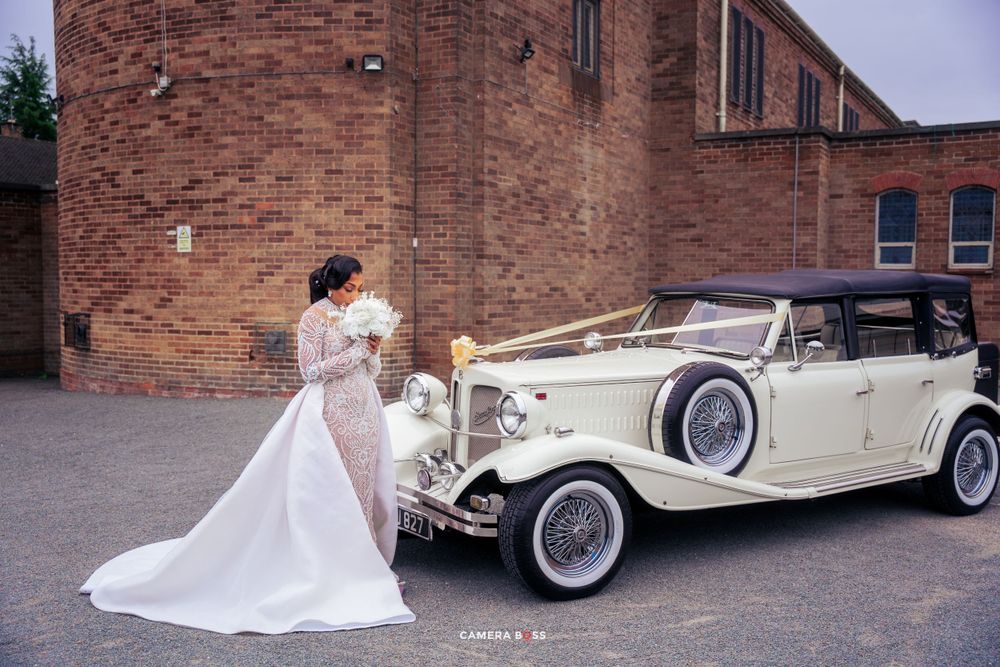 Elegant vintage cream-colored Rolls Royce wedding car parked beside brick building at twilight.
