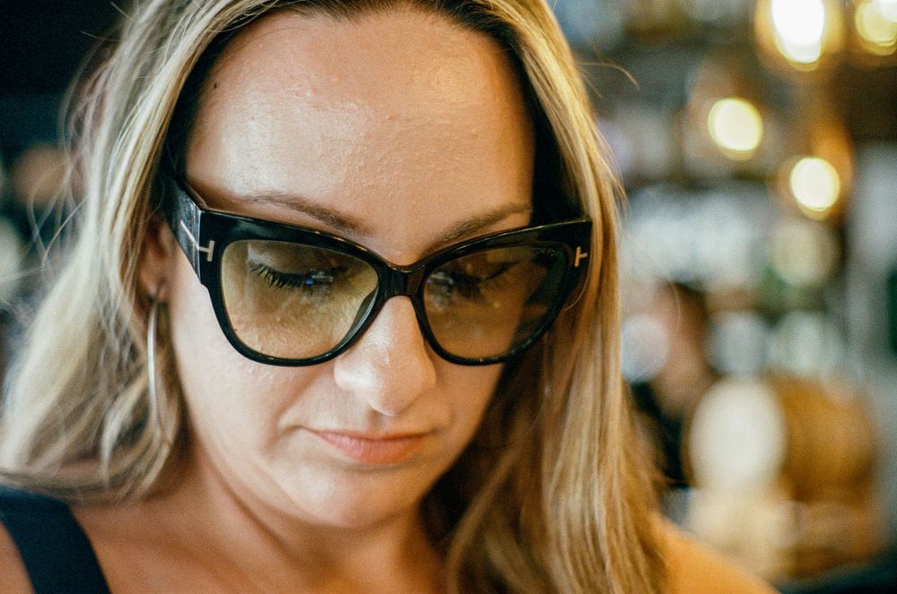 Close up portrait of a woman wearing stylish cat eye glasses with soft lighting in the background.