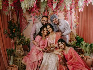 Family gathering under floral decorations with pink and coral outfits against a decorated backdrop.