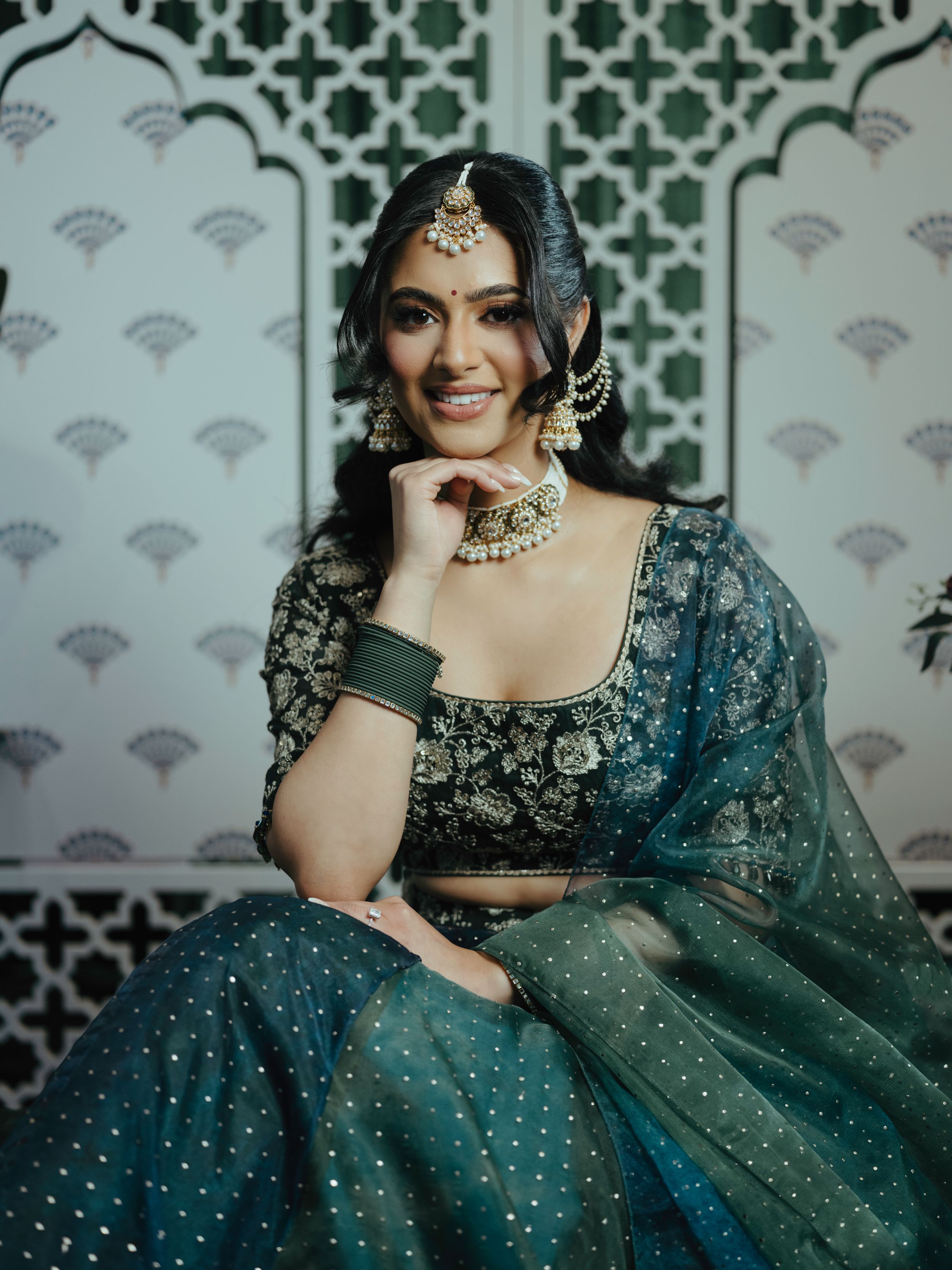 Traditional Indian bridal wear featuring an embellished teal lehenga with intricate embroidery and matching jewelry.