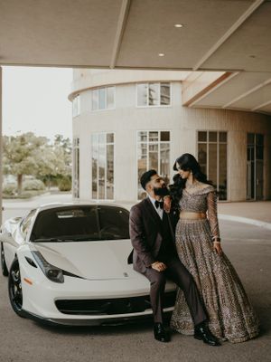 Elegant couple posing with white Ferrari at upscale venue in fusion wedding attire.