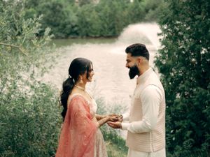 A couple stands on a peaceful garden path as they share a romantic moment together in soft natural lighting.