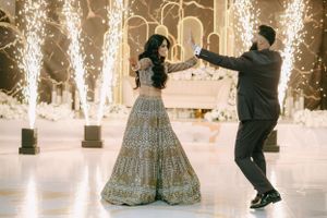 Couple dancing on an illuminated dance floor with sparkler fountains creating a magical backdrop at an elegant celebration.