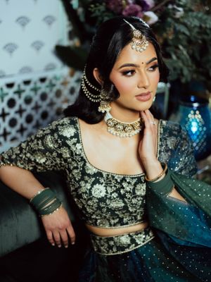 Traditional South Asian attire featuring an embellished dark crop top and lehenga with intricate beadwork and jewelry.